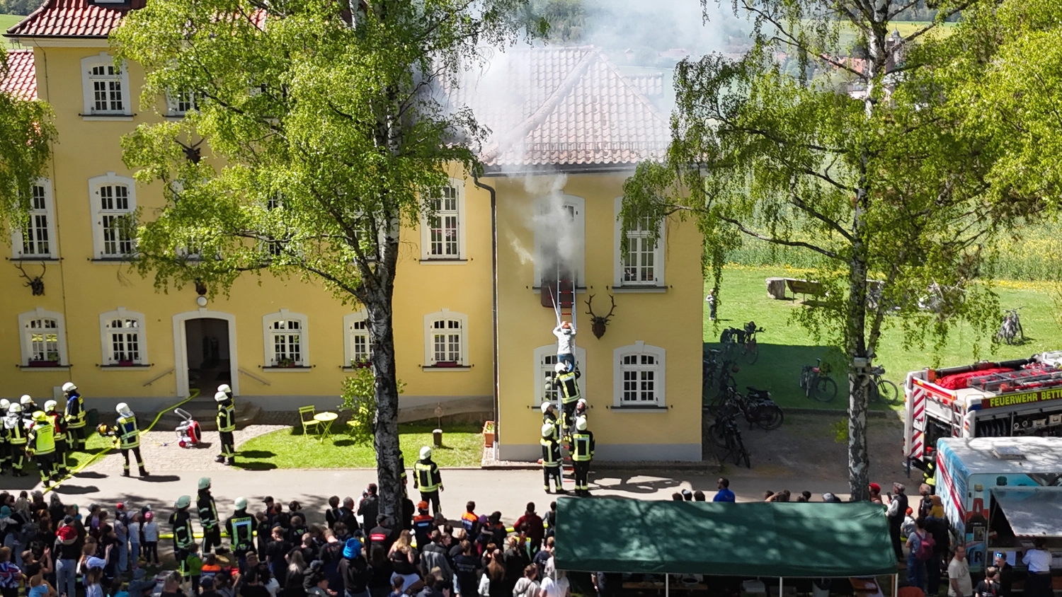 Kreisfeuerwehrverband Schmalkalden-Meiningen e.V. - Koordiniert die Aktivitäten und Veranstaltungen der Feuerwehr - Ein Feuerwehrmann in voller Schutzausrüstung und mit Atemschutzmaske hält einen Feuerwehrschlauch vor einem Feuerwehrfahrzeug.