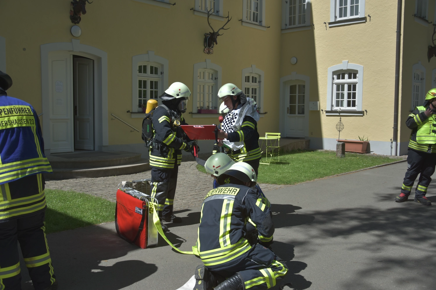 Kreisfeuerwehrverband Schmalkalden-Meiningen e.V. - Koordiniert die Aktivitäten und Veranstaltungen der Feuerwehr - Ein Feuerwehrmann in voller Schutzausrüstung und mit Atemschutzmaske hält einen Feuerwehrschlauch vor einem Feuerwehrfahrzeug.